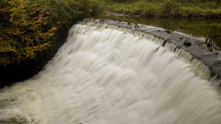 A view of the weir at Quarry Bank, with a huge volume of water cascading over